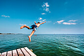 Junge springt von einem Steg, Südstrand, Burgtiefe, Fehmarn, Ostsee, Schleswig-Holstein, Deutschland