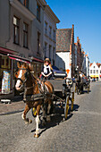 Touristen genießen Fahrt mit Pferdekutsche nahe Marktplatz in der Altstadt, Brügge, Flandern, Belgien, Europa