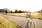 Junge Frau fährt Fahrrad an einem sonnigen Tag, Tannheimer Tal, Tirol, Österreich