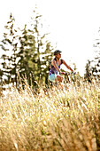 Young woman riding her bike near a meadow on a sunny day, Tannheimer Tal, Tyrol, Austria