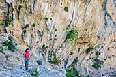Woman hiking Selvaggio Blu crossing rock face with tufa, Selvaggio Blu, National Park of the Bay of Orosei and Gennargentu, Sardinia, Italy