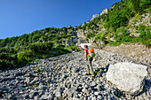 Woman ascending through scree to fixed rope route Pidinger Klett, Hochstaufen, Chiemgau Alps, Chiemgau, Upper Bavaria, Bavaria, Germany