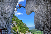 Woman ascending on steep fixed rope route, fixed rope route Pidinger Klettersteig, Hochstaufen, Chiemgau Alps, Chiemgau, Upper Bavaria, Bavaria, Germany