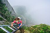 Frau steigt über Leiter zum Steineberg auf, Nebel im Hintergrund, Steineberg, Nagelfluhkette, Allgäuer Alpen, Allgäu, Schwaben, Bayern, Deutschland