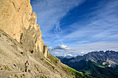 Woman hiking beneath rock face, Rotwand, Rosengarten, UNESCO world heritage Dolomites, Dolomites, Trentino, Italy