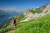 Frau wandert durch Blumenwiese auf Malatschkopf und Stanskogel zu, Lechtaler Alpen, Tirol, Österreich