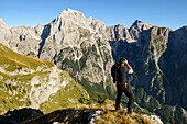 Hiker photographing craggy mountains, Mangart, Bovsko, Slovenia, Mangart, Bovsko, Slovenia