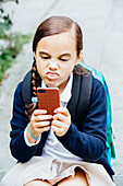 Mixed race girl making a face at cell phone, Seattle, WA, USA