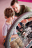 Caucasian father teaching son to repair bicycle, Los Angeles, CA, USA
