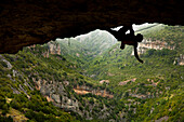Climber hanging from rock formation, Rodellar, Aragon, Spain