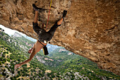 Climber hanging from rock formation, Rodellar, Aragon, Spain