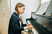 Mixed race girl playing piano, Seattle, WA, USA