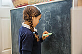 Mixed race girl drawing on chalkboard, Seattle, WA, USA