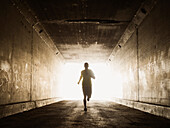 Caucasian man running in urban tunnel, Los Angeles, California, USA