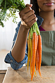 Mixed race woman holding bunch of carrots, Jersey City, New Jersey, USA