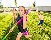 Caucasian children playing in sprinkler in backyard, Lehi, Utah, USA