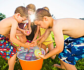 Caucasian children playing with water balloons in backyard, Lehi, Utah, USA