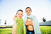 Caucasian boys wearing towel capes in backyard, Lehi, Utah, USA