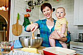 Caucasian mother cooking with baby in kitchen, C1