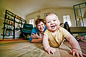 Caucasian mother and baby playing on living room floor, C1