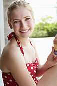 Smiling woman in swimsuit eating ice cream cone, New York, New York, United States