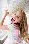Caucasian girl having pillow fight in bedroom, Jersey City, New Jersey, USA