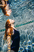 Teenage girl with red hair swimming underwater in pool, Bainbridge Island, WA, United States