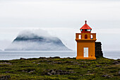 Orange lighthouse on rocky remote cliff, Rydarfjordur, Iceland, Iceland