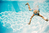 Caucasian boy swimming underwater in pool, Huntington Station, New York, USA