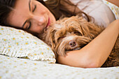 Caucasian woman hugging pet dog in bed, Jersey City, New Jersey, USA