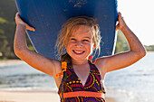 Caucasian girl holding paddle board, Kauai, Hawaii, USA