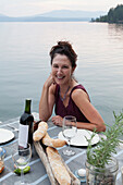 Caucasian woman smiling at table near lake, Hope, Idaho, USA