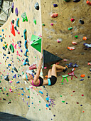 Caucasian woman climbing indoor rock wall, Ogden, Utah, USA