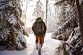 Mixed race man walking in snowy forest, C1
