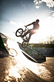 Caucasian man riding BMX bicycle at skate park, C1