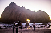 Camera on self-timer taking photograph of couple on beach, Big Sur, California, United States, Big Sur, California, United States