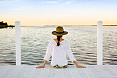 Caucasian woman sitting at edge of pier, Florida Keys - Big Pine Key, Florida, United States