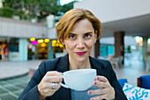 Caucasian businesswoman drinking coffee at sidewalk cafe, Los Angeles, CA, USA