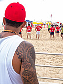 Brazil, Rio de Janeiro, Copacabana beach, a Carioca tatooed watching a beach volleyball game