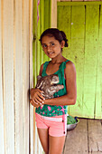 Brazil, Amazonas, Manaus (capital of Amazonas), Rio Negro, young Indian girl holding a sloth in front of her floating house