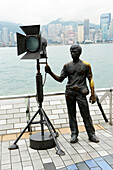 Statue and skyline along the Avenue of Stars attraction near the waterfront at Tsim Sha Tsui. The promenade honours celebrities of the Hong Kong industry as the famous city attraction
