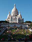 France, Paris, butte Montmartre, garden of Sacré coeur basilica, tourists sitting on the grass, summer night