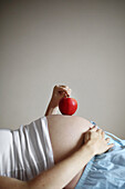An apple on the belly of a 7 months pregnant woman