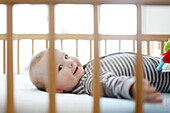 Baby boy lying down in his crib and smiling