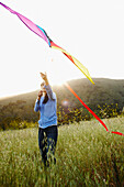 Asian woman flying kite in field