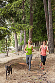 Caucasian women running with dog in forest