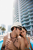 Hispanic couple hugging poolside