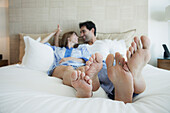 Hispanic couple laying on bed with bare feet