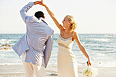 Newlywed couple dancing on beach