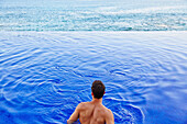 Man relaxing in infinity pool